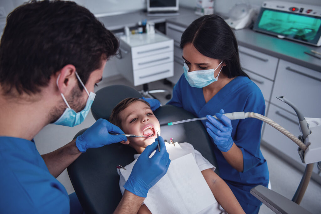 Two beautiful young dentist are treating cute little boy's teeth